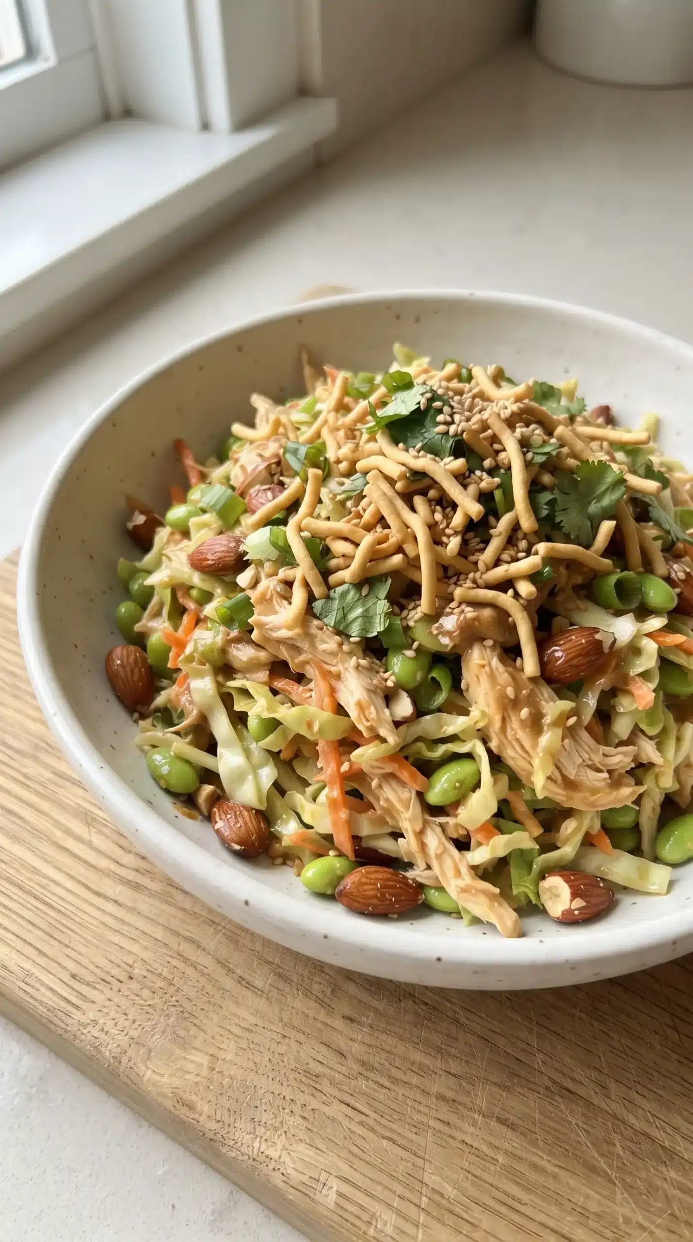 Finished Asian chicken salad with edamame, almonds, vegetables, and crunchy chow mein noodles