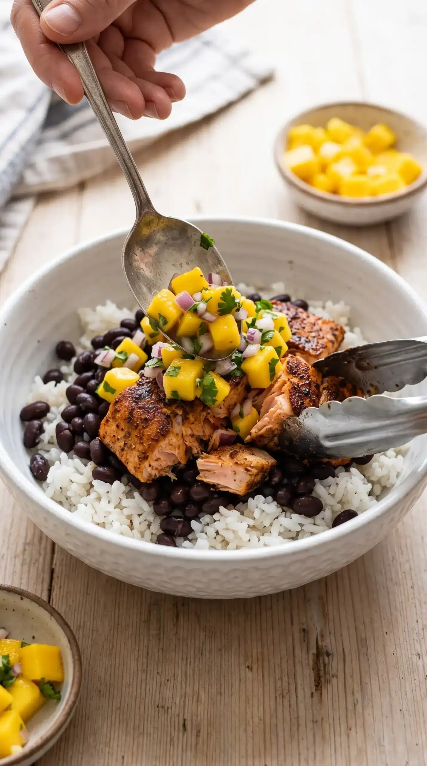 Jerk salmon bowl assembly with rice, beans, salmon, and mango salsa