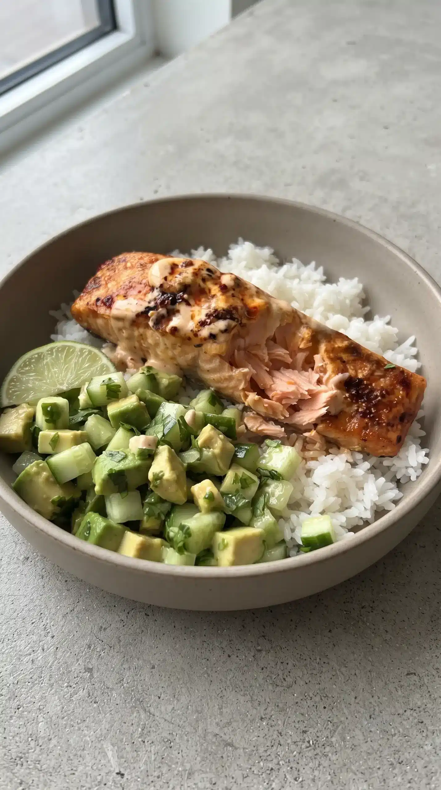 Bang bang salmon bowl with creamy sweet chili salmon, rice, and avocado cucumber salsa