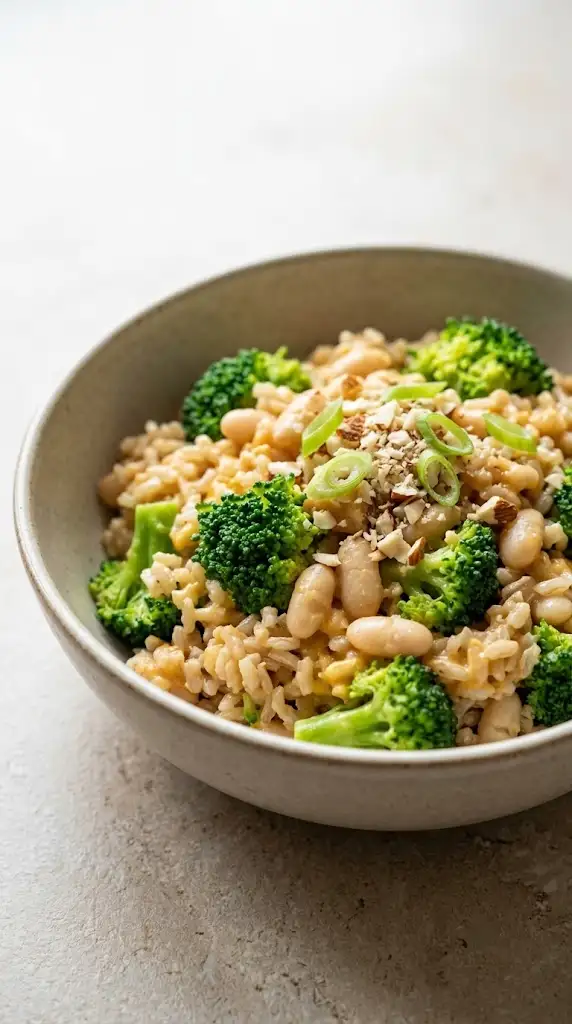 Bowl of broccoli cheese rice with brown rice, broccoli, white beans, and creamy sauce