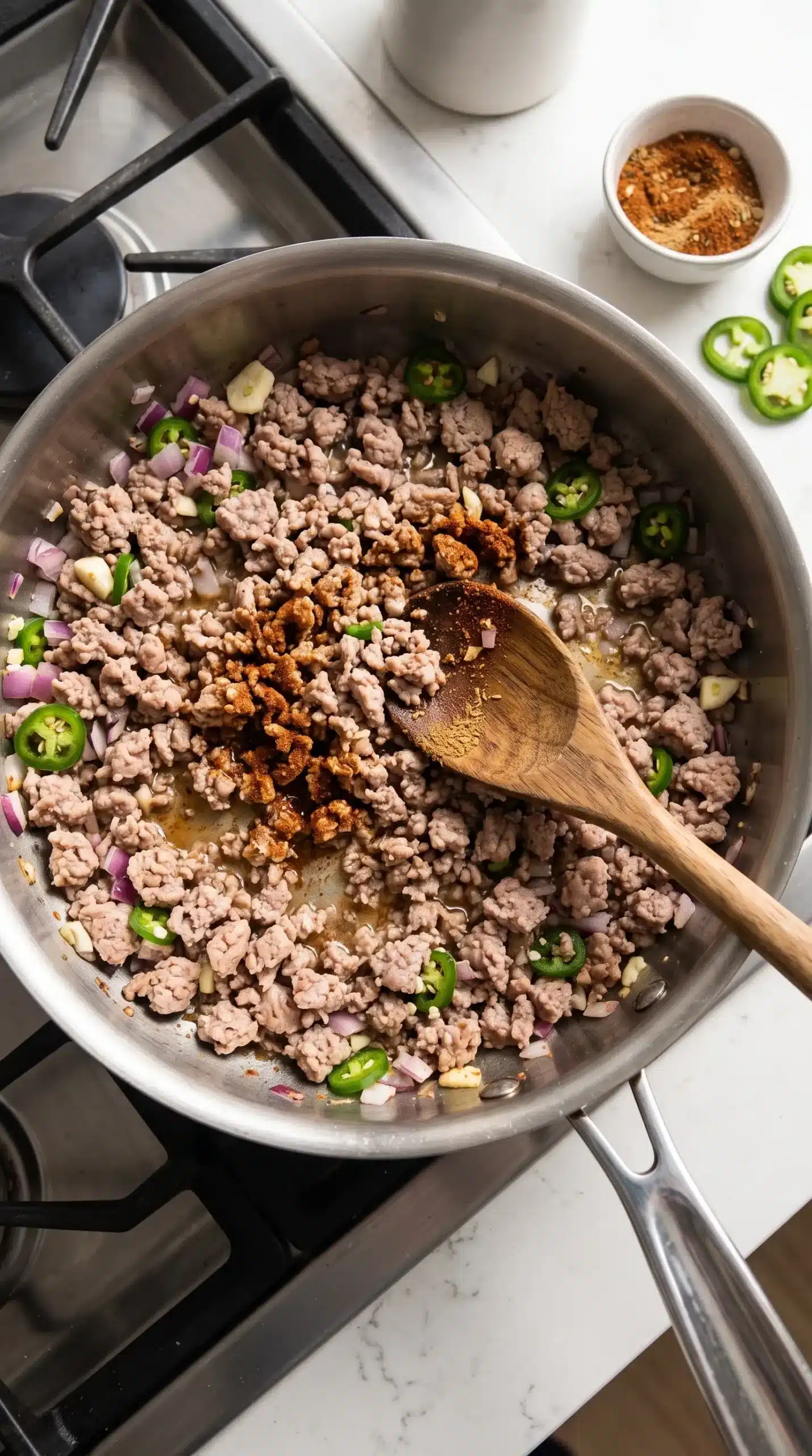 Ground turkey browning with onion, garlic, and jalapenos in a skillet