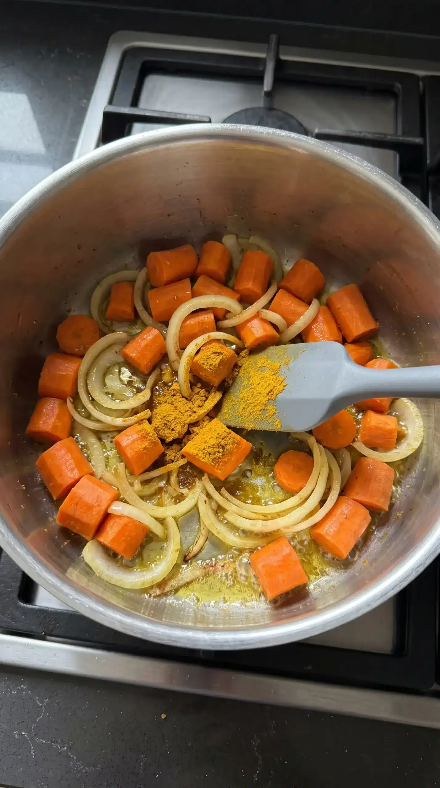 Carrots and onions sautéing with curry powder as the base for carrot soup