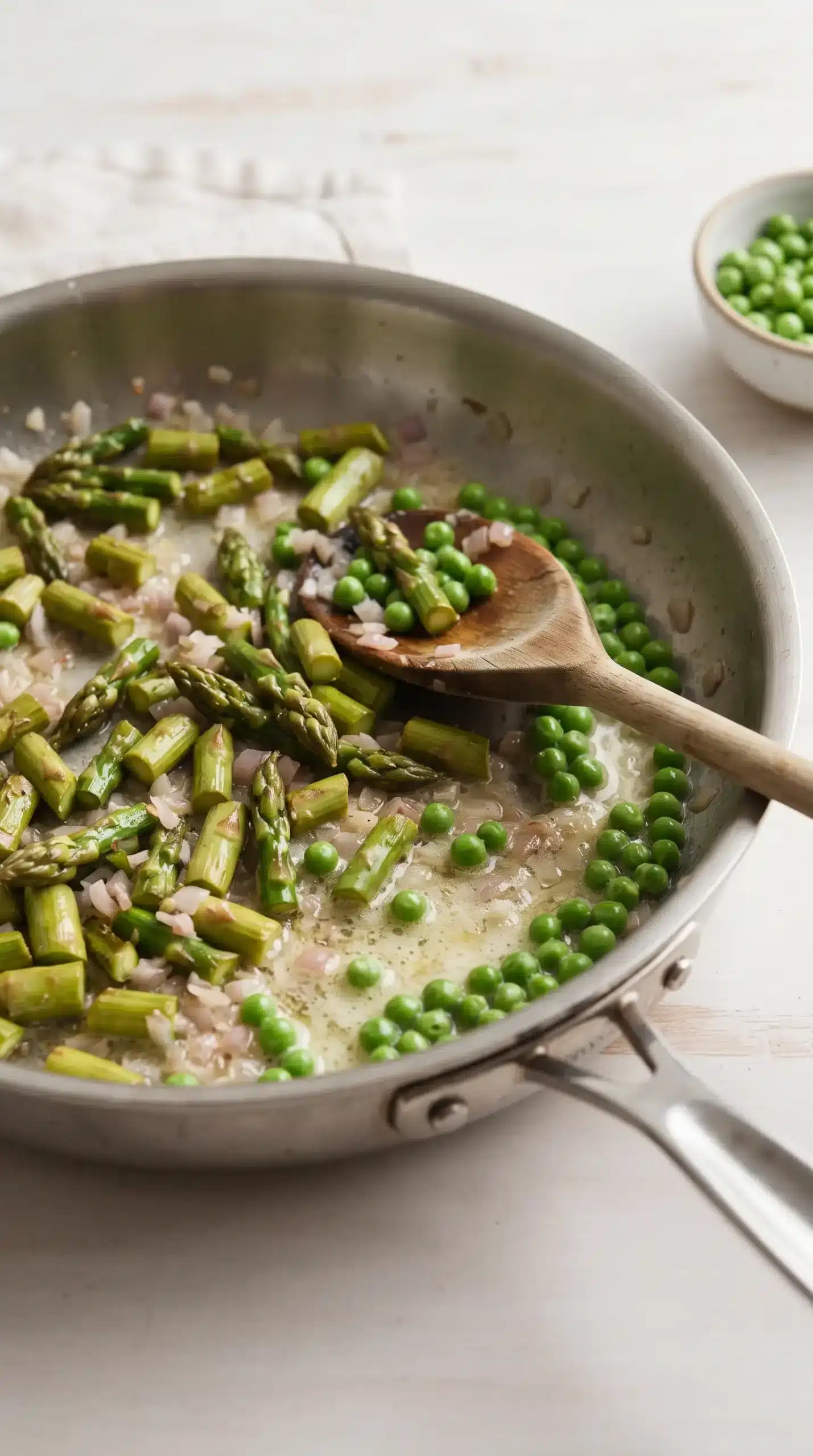 Chopped asparagus cooking with butter and shallot in a skillet for vegetable saute