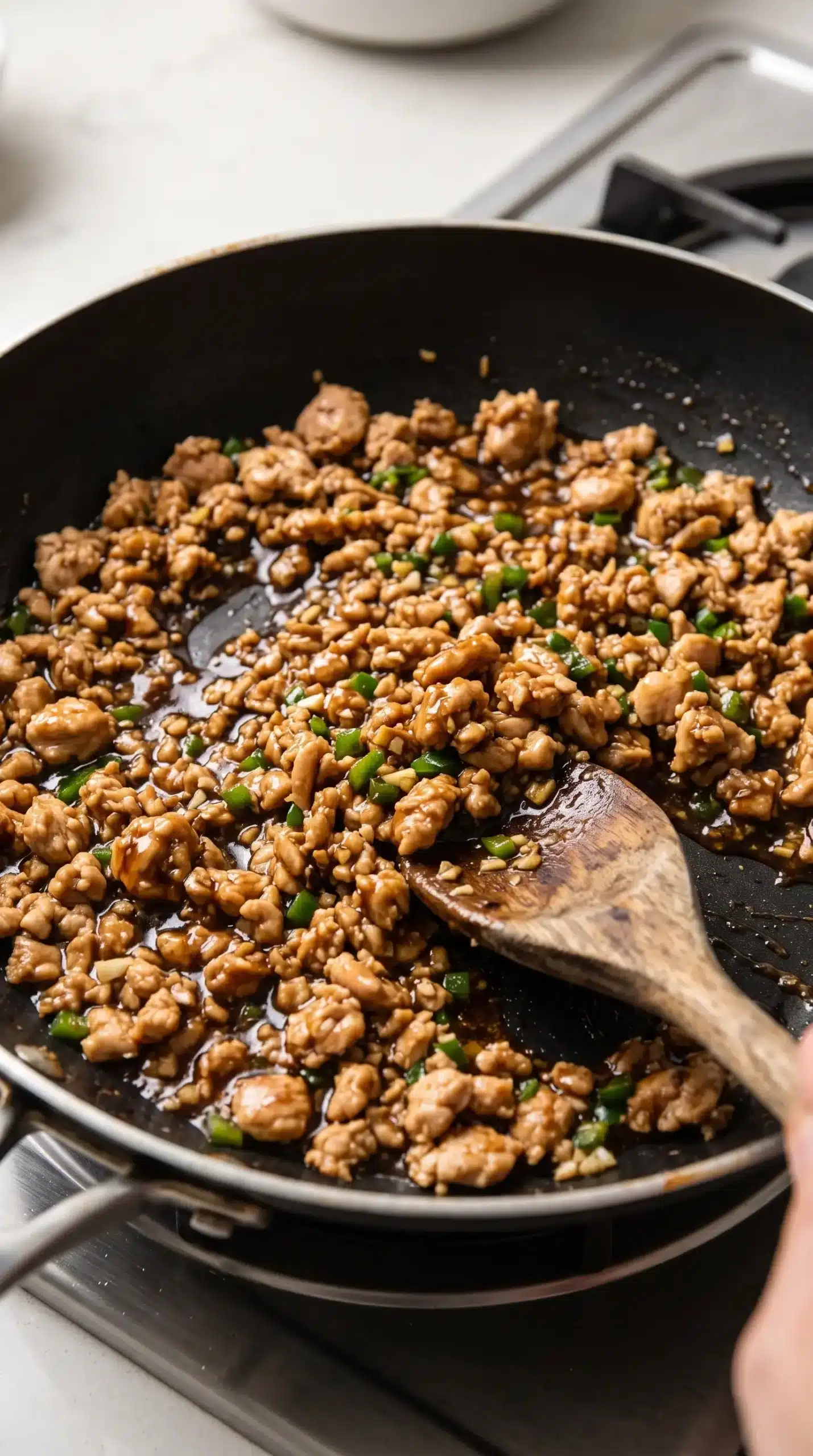 Ground chicken cooking with garlic, jalapeno, and sauce in a skillet
