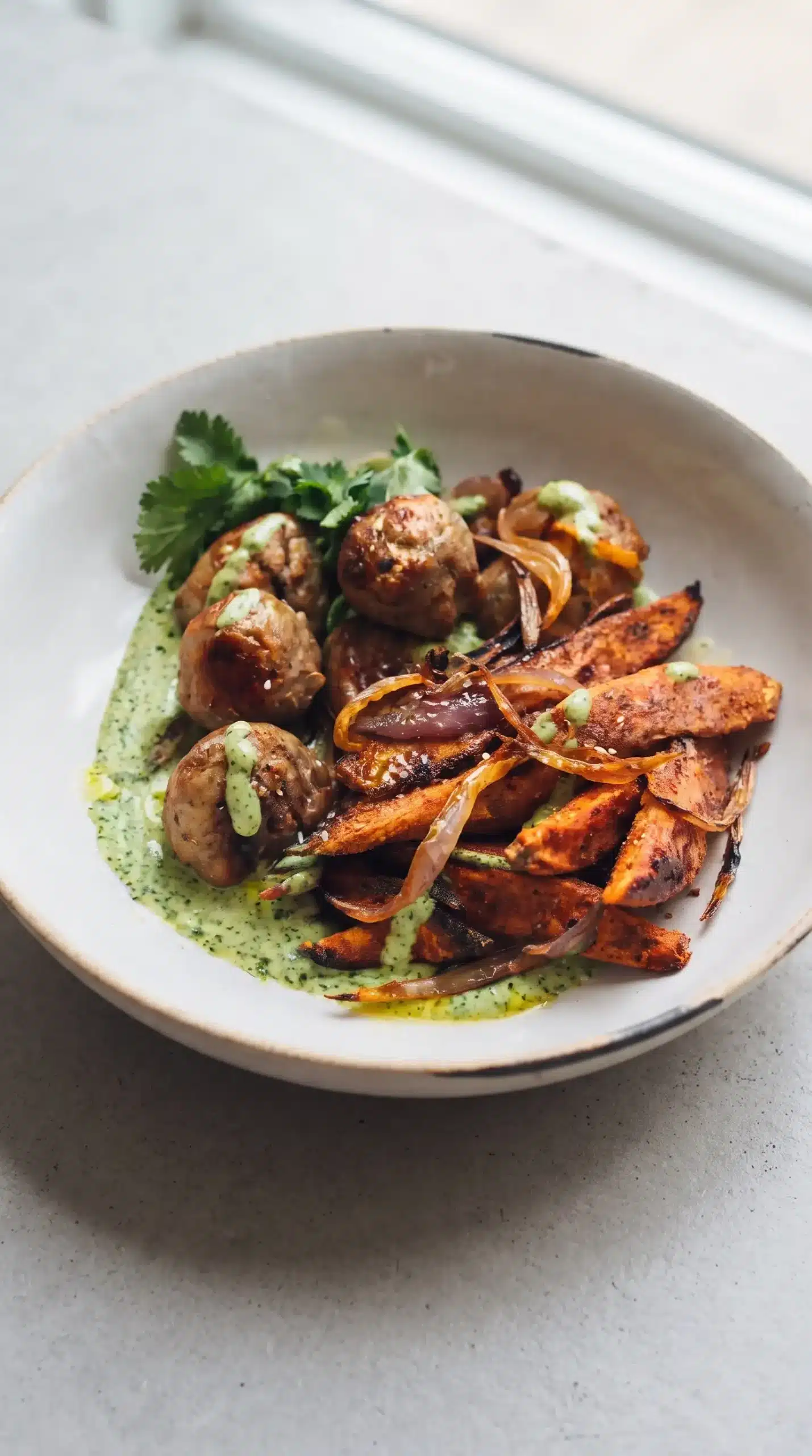 Finished avocado mojo bowl with roasted sweet potatoes, chicken meatballs, and green sauce