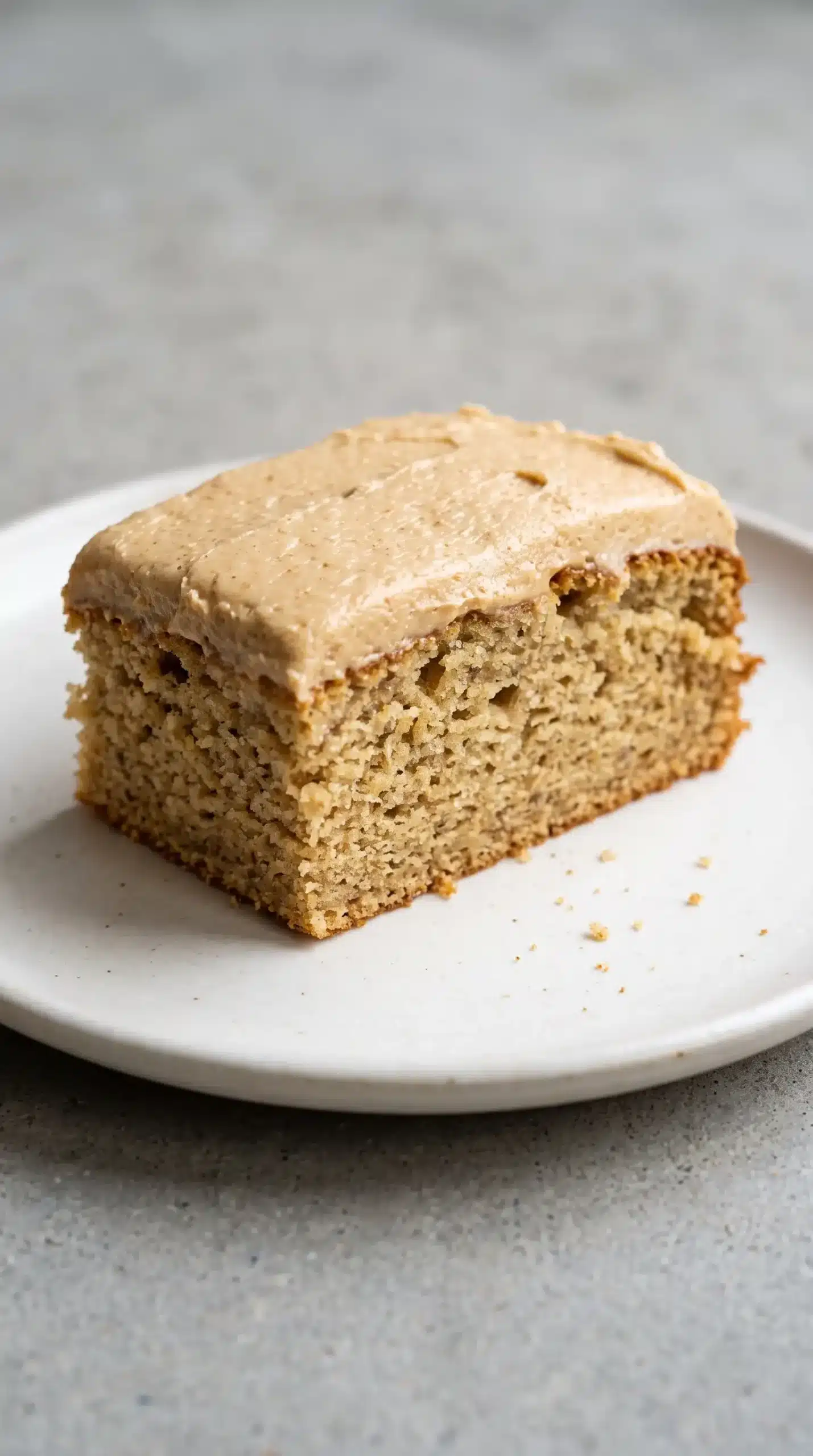 Slice of banana cake topped with creamy peanut butter frosting on a plate