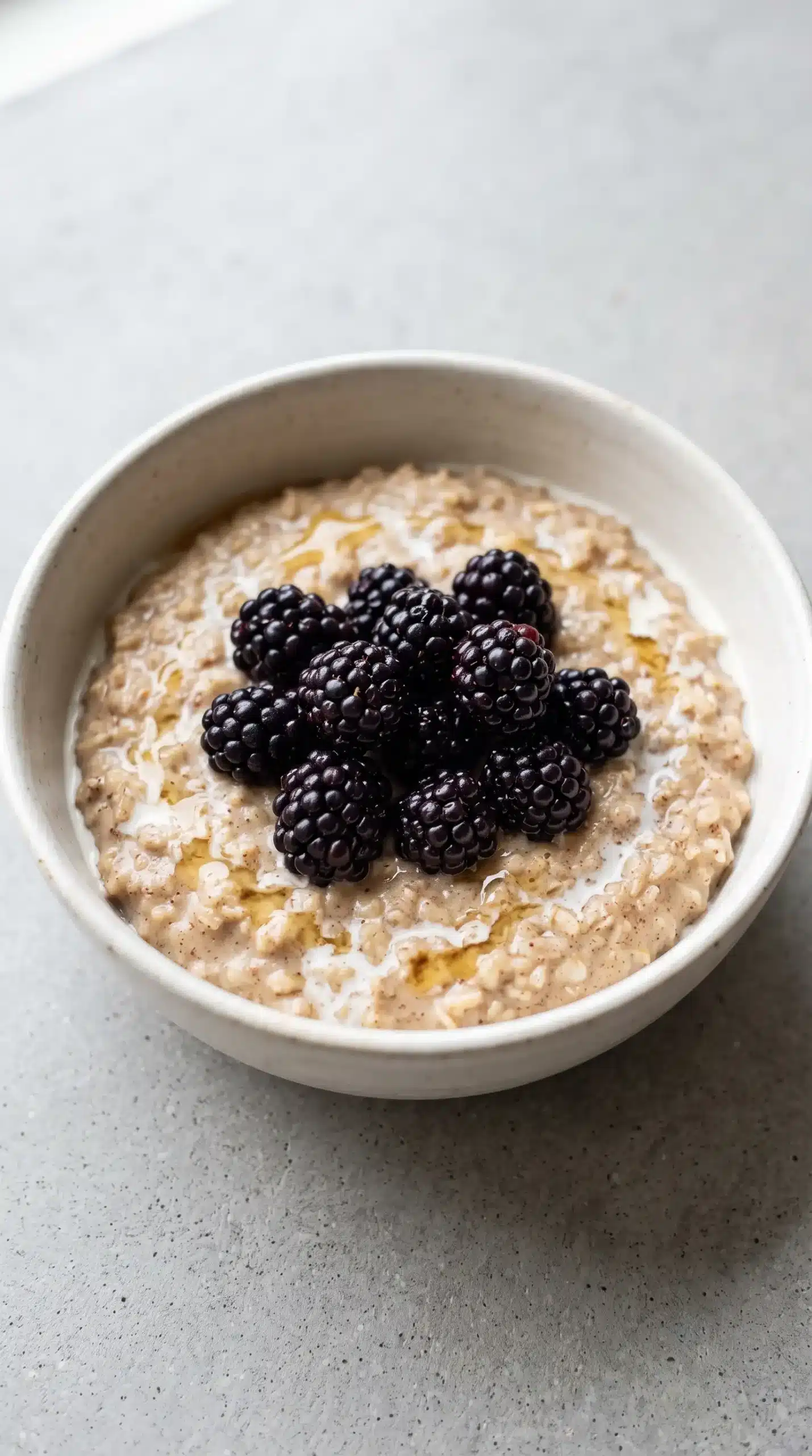 Finished blackberries and cream oats with honey and berries served in a ceramic breakfast bowl