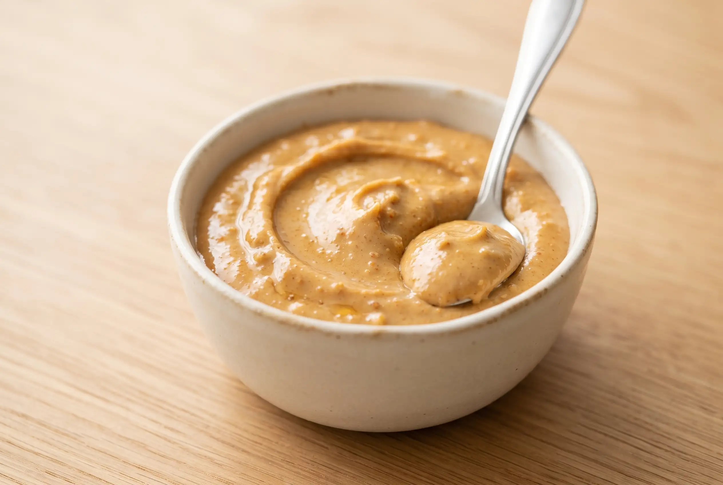 Bowl of smooth homemade peanut butter spread made from dry roasted peanuts