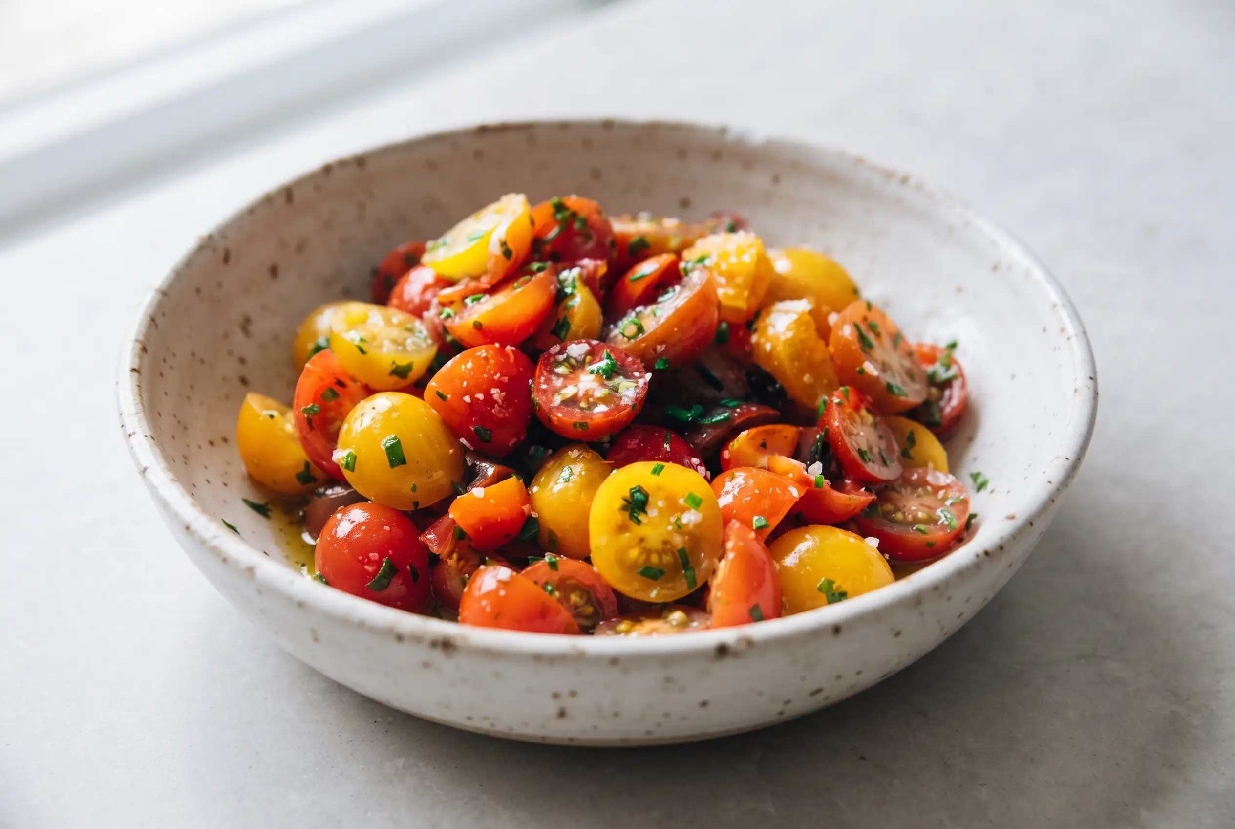 Marinated tomatoes with olive oil, garlic, vinegar, and herbs in a ceramic bowl