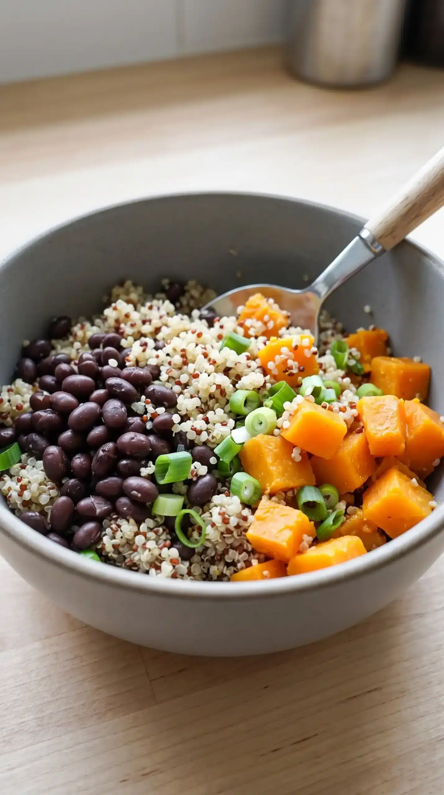 Bowl of quinoa, black beans, squash cubes, and scallions prepared for wrap filling