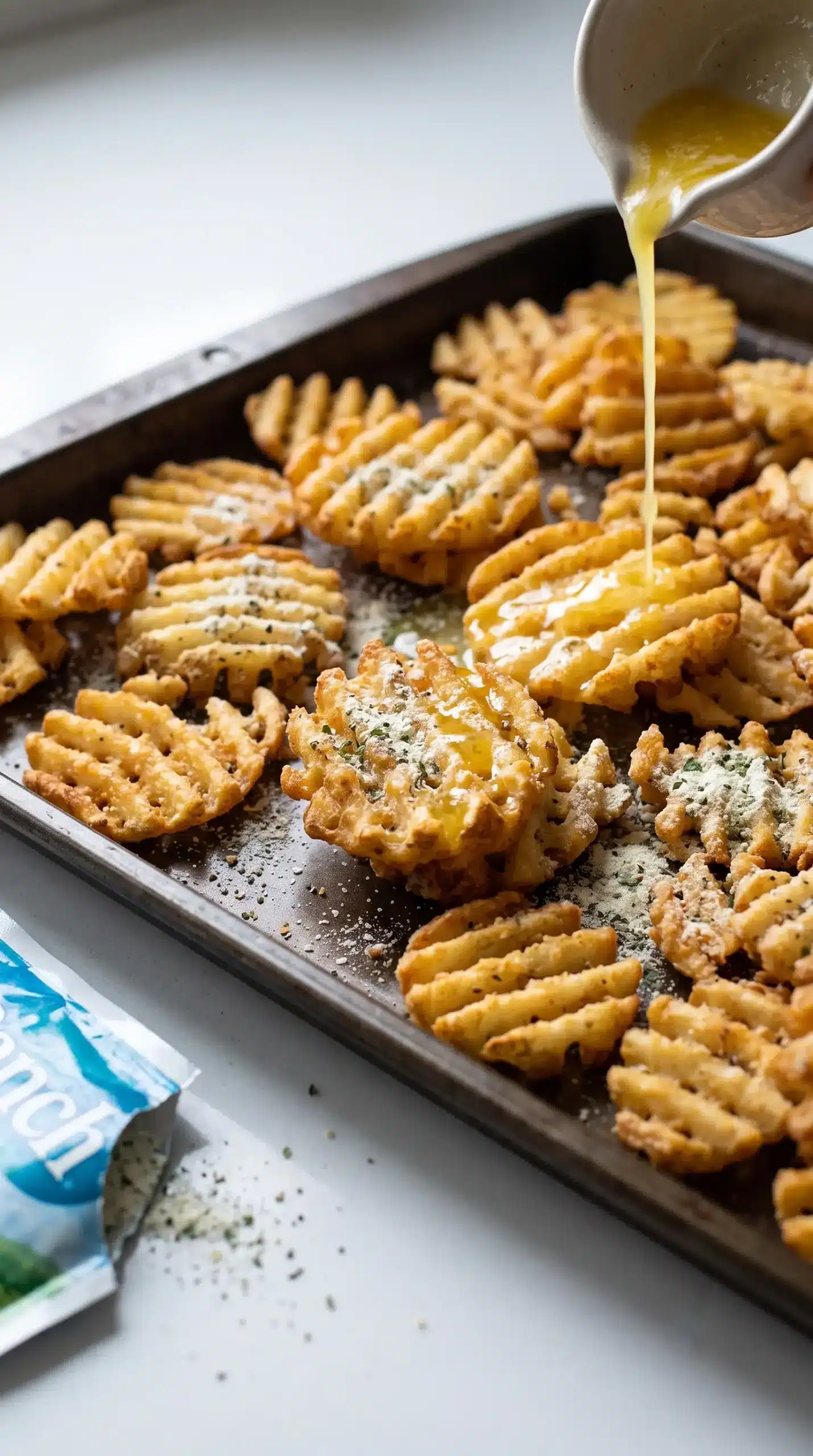 Ranch seasoned waffle fries on a baking sheet being prepared for burger bowls