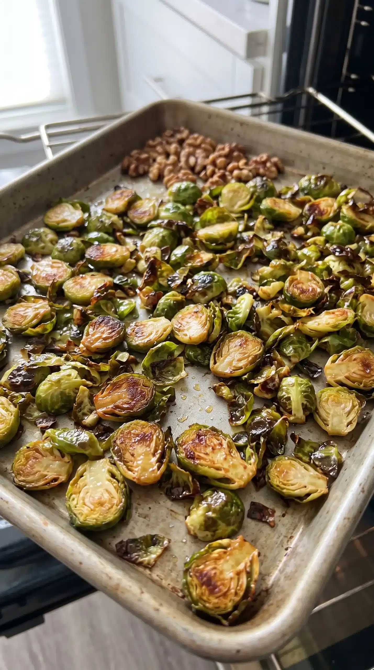 Shaved Brussels sprouts roasting on a sheet pan with browned edges and toasted walnuts