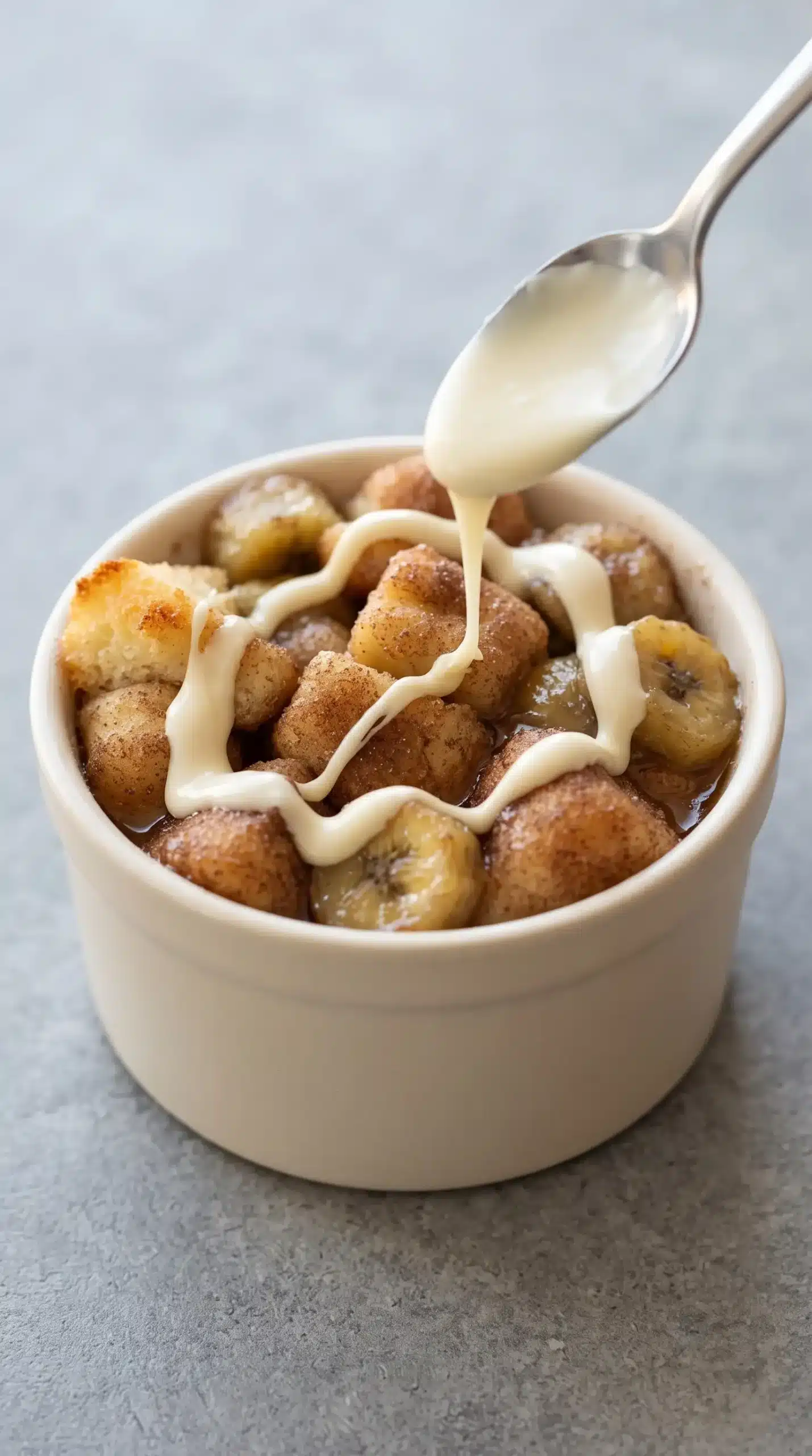 Melted white chocolate drizzled over warm banana monkey bread in a ramekin