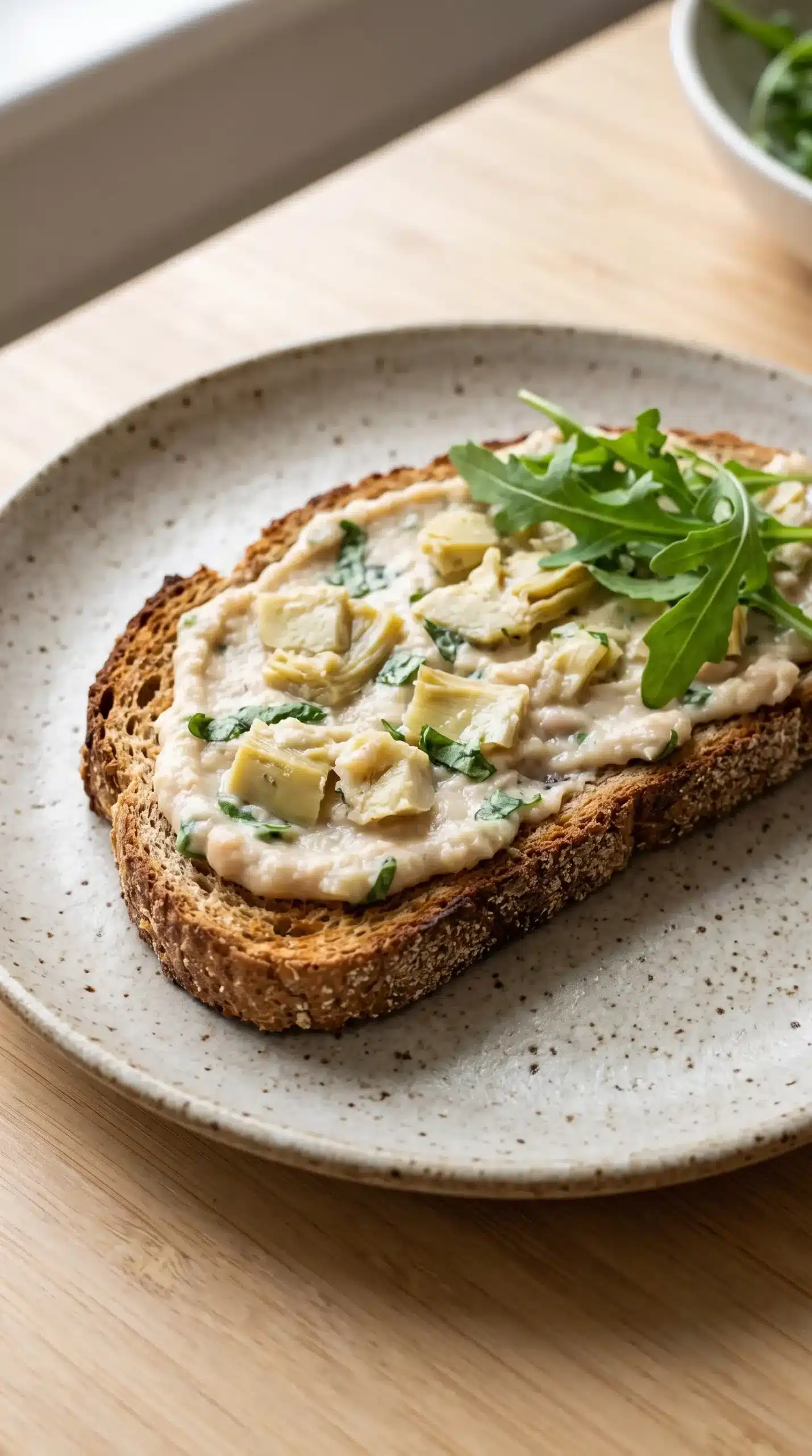 Crisp whole wheat toast topped with creamy white bean spread, artichokes, basil, and greens